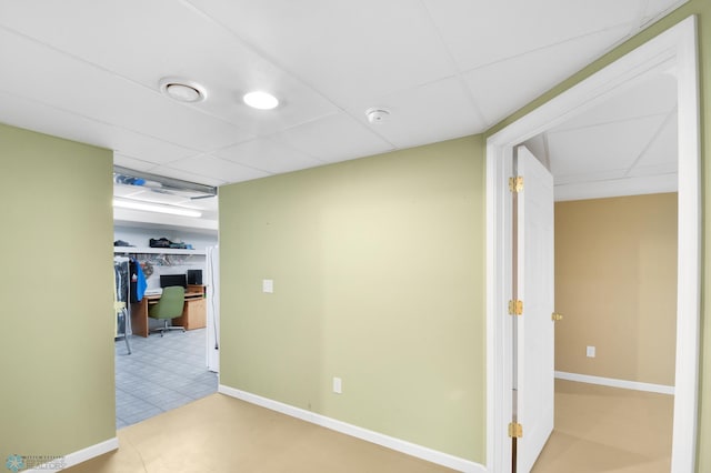 below grade area featuring tile patterned floors, a paneled ceiling, and baseboards