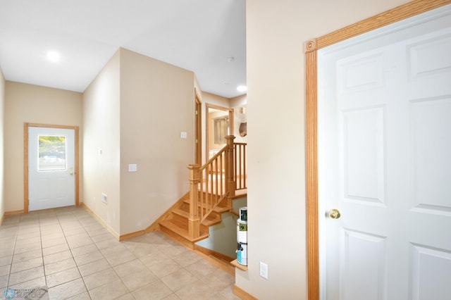 entryway with light tile patterned floors, baseboards, and stairs