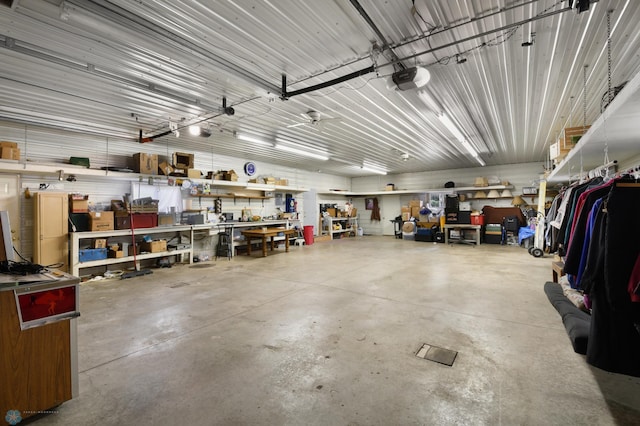 garage with a workshop area, a garage door opener, and metal wall