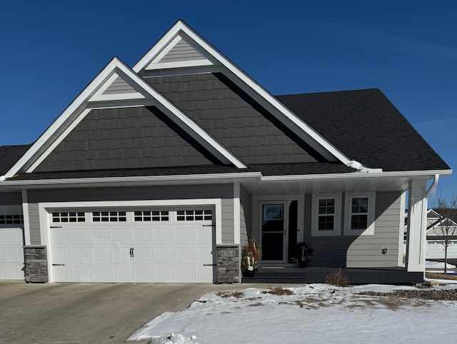 view of front of home featuring a garage, driveway, a shingled roof, and stone siding