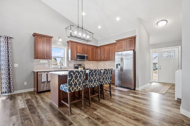 9764 Saint Andrews Dr, Elko New Market, MN 55020 - kitchen featuring appliances with stainless steel finishes, a kitchen island, a breakfast bar area, light countertops, and tasteful backsplash