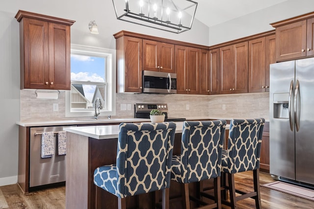 9764 Saint Andrews Dr, Elko New Market, MN 55020 - kitchen with stainless steel appliances, a kitchen island, wood finished floors, light countertops, and decorative backsplash