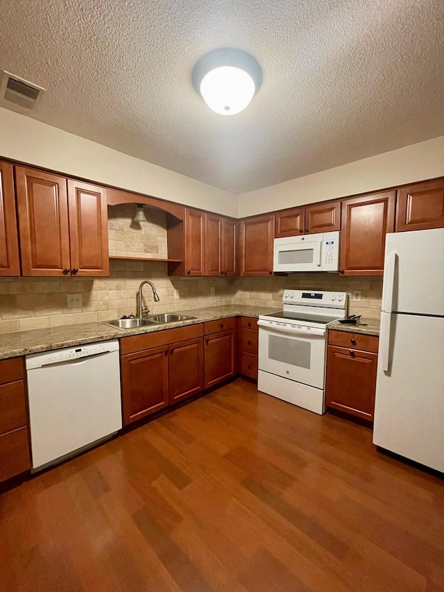 kitchen with white appliances, dark wood-type flooring, a sink, visible vents, and tasteful backsplash