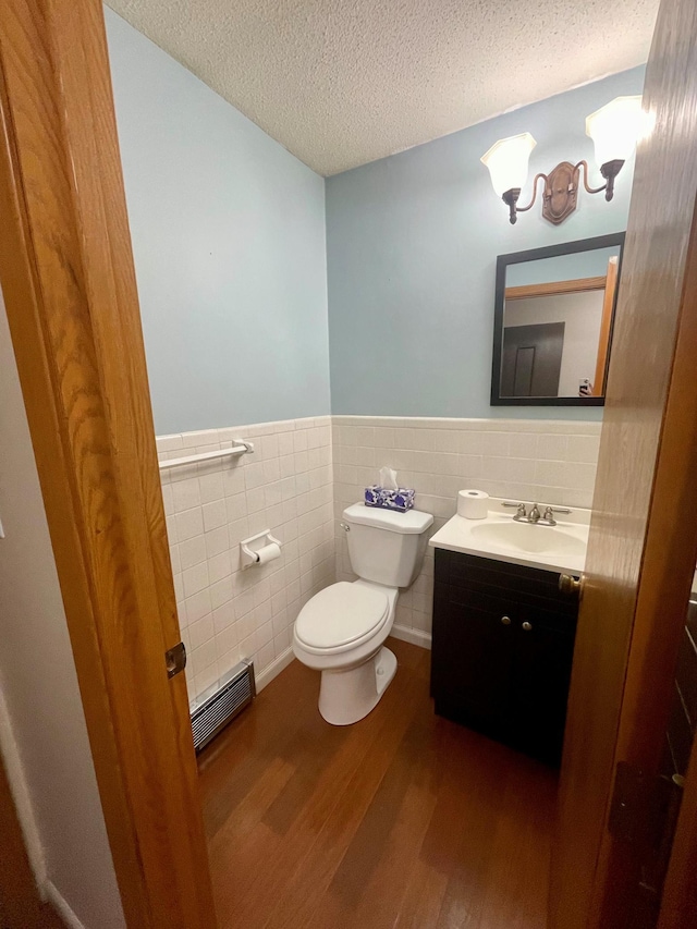 bathroom featuring wainscoting, toilet, wood finished floors, a textured ceiling, and vanity