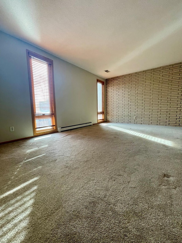 carpeted spare room with plenty of natural light, a textured ceiling, a baseboard radiator, and visible vents