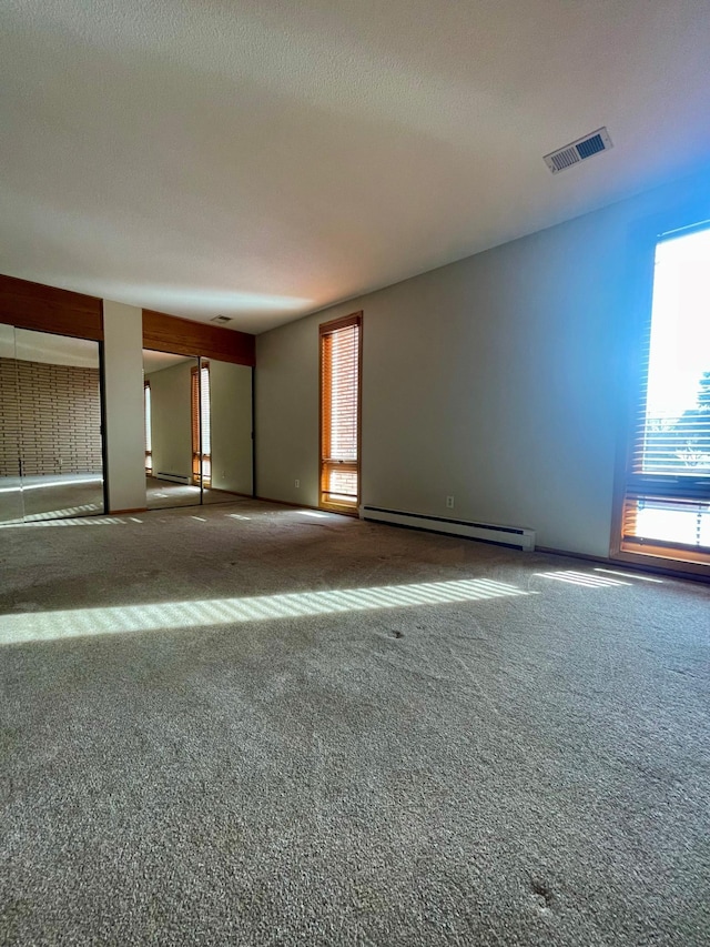 unfurnished room featuring a baseboard radiator, carpet flooring, visible vents, and a textured ceiling