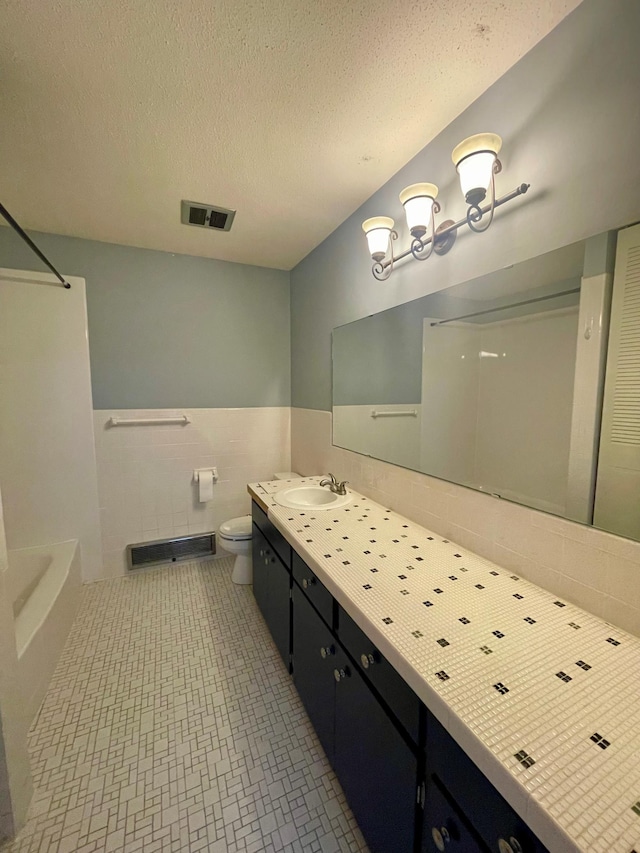 bathroom with visible vents, wainscoting, toilet, a textured ceiling, and vanity