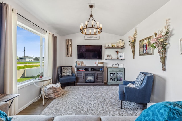 living room featuring vaulted ceiling, baseboards, wood finished floors, and a chandelier