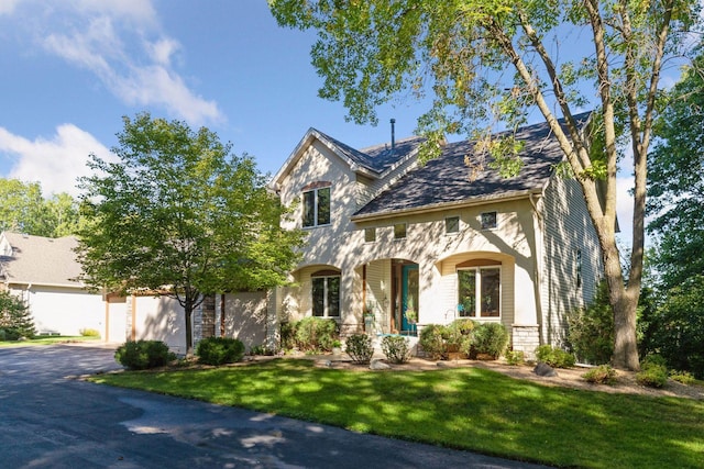 view of front of property with aphalt driveway, covered porch, and a front lawn