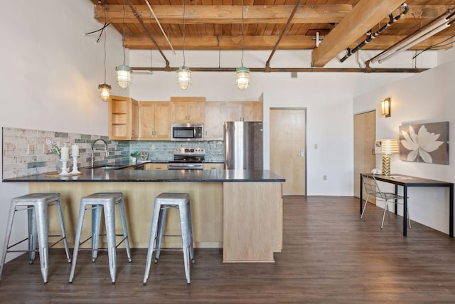 kitchen featuring stainless steel appliances, a peninsula, a sink, light brown cabinetry, and dark countertops