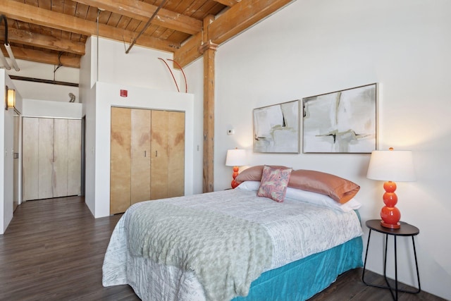 bedroom with a closet, wooden ceiling, wood finished floors, and beam ceiling