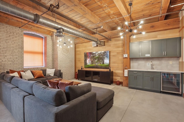 living area with wine cooler, beam ceiling, wooden walls, brick wall, and concrete flooring