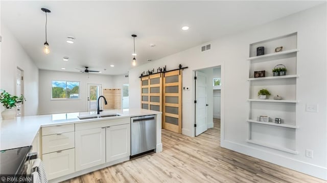 kitchen with appliances with stainless steel finishes, light countertops, a sink, and a barn door