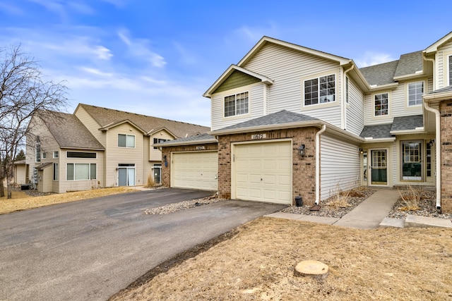 view of property featuring a garage, brick siding, a shingled roof, and aphalt driveway