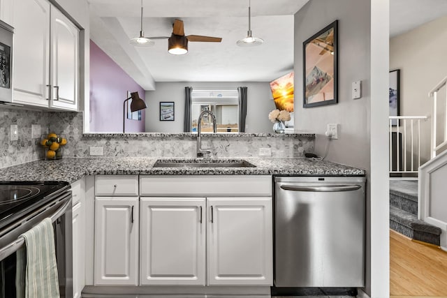 kitchen with appliances with stainless steel finishes, white cabinets, a sink, and dark stone countertops