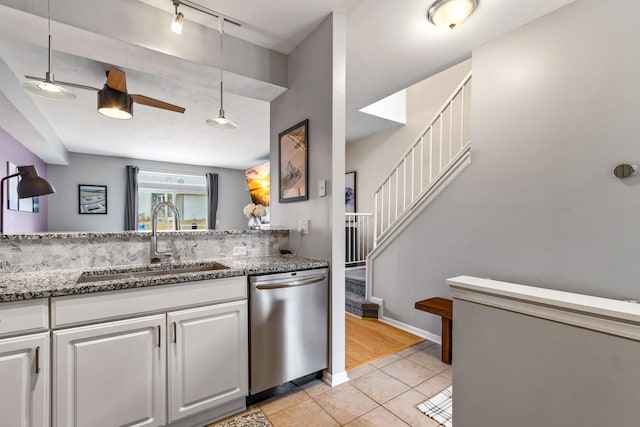 kitchen with white cabinets, light tile patterned flooring, a sink, light stone countertops, and dishwasher