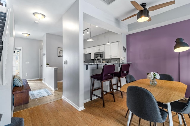 dining area with baseboards, visible vents, a ceiling fan, and light wood-style floors