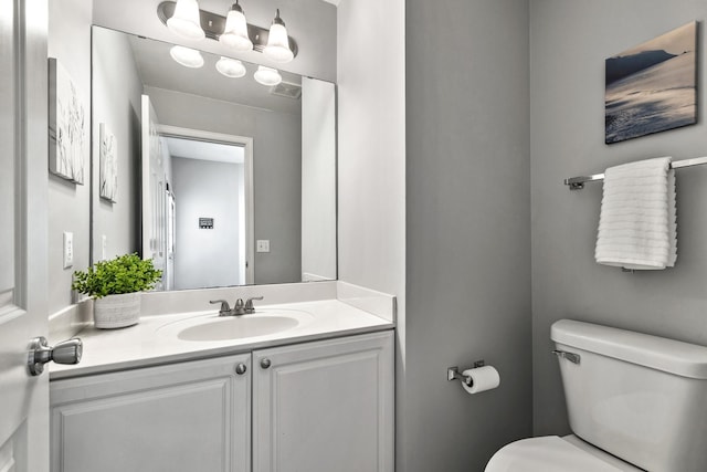 half bathroom featuring toilet, visible vents, and vanity