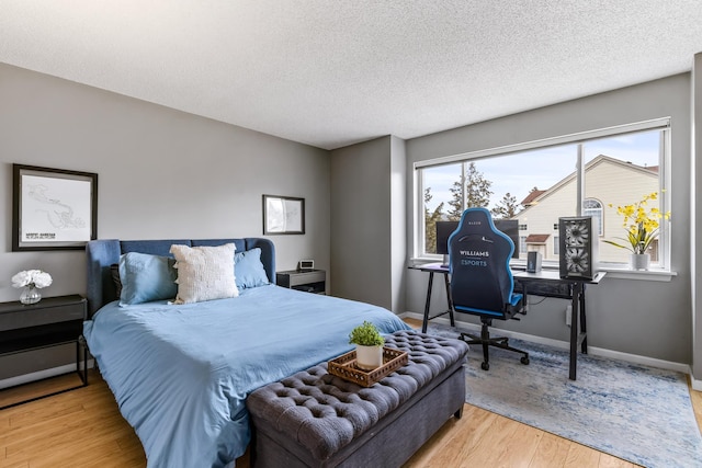 bedroom with multiple windows, baseboards, and wood finished floors