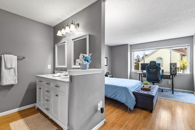 bathroom featuring vanity, a textured ceiling, baseboards, and wood finished floors