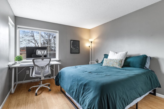 bedroom featuring a textured ceiling, wood finished floors, and baseboards