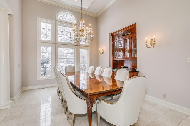 dining room with light tile patterned floors, decorative columns, baseboards, ornamental molding, and a chandelier