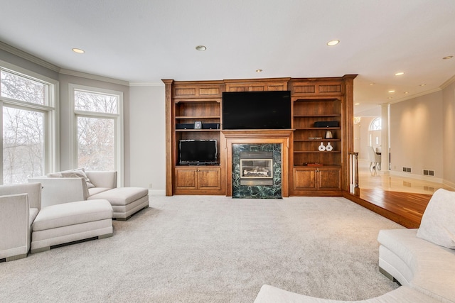 carpeted living room with recessed lighting, visible vents, baseboards, a high end fireplace, and crown molding