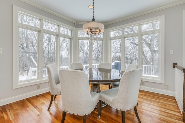 dining space with a chandelier, ornamental molding, wood finished floors, and baseboards