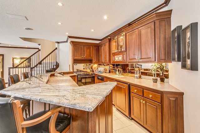 kitchen with brown cabinets, stainless steel range, light tile patterned floors, a sink, and a kitchen bar