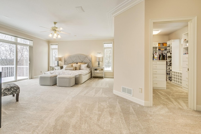 bedroom with a walk in closet, light carpet, crown molding, and multiple windows