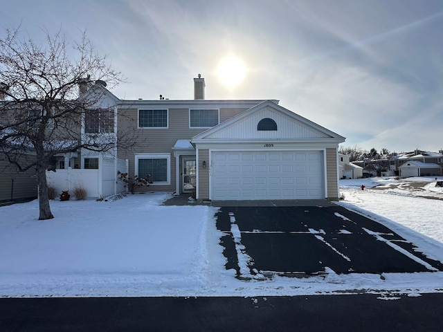 view of front of house with aphalt driveway, an attached garage, and a chimney