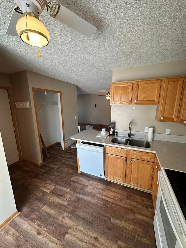 kitchen with white appliances, a peninsula, dark wood-style flooring, a sink, and light countertops