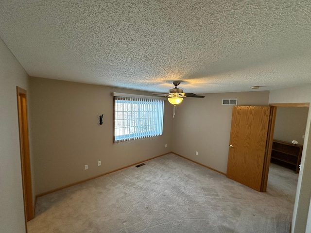 unfurnished bedroom featuring visible vents, baseboards, light colored carpet, and a ceiling fan