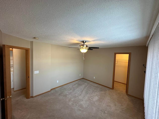 unfurnished bedroom with a walk in closet, light carpet, a textured ceiling, a closet, and baseboards