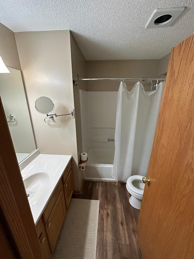 full bathroom featuring toilet, vanity, shower / tub combo, wood finished floors, and a textured ceiling