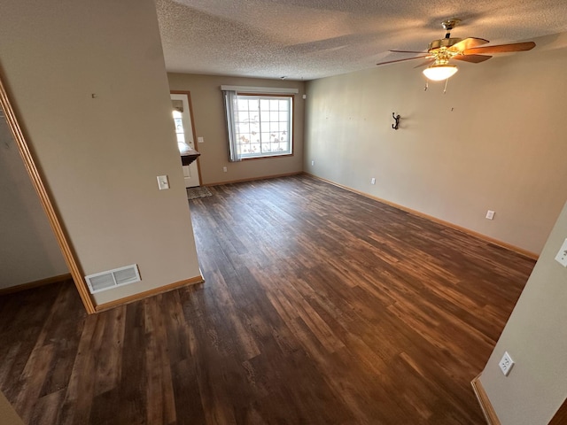 unfurnished living room with visible vents, baseboards, dark wood-type flooring, and a textured ceiling