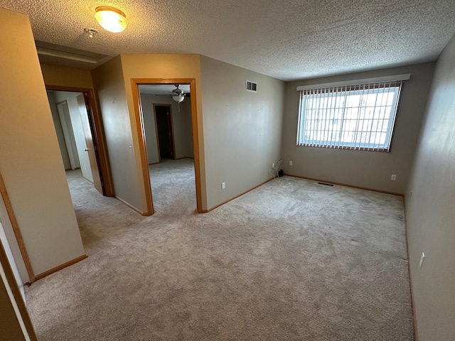 spare room with visible vents, a textured ceiling, baseboards, and carpet