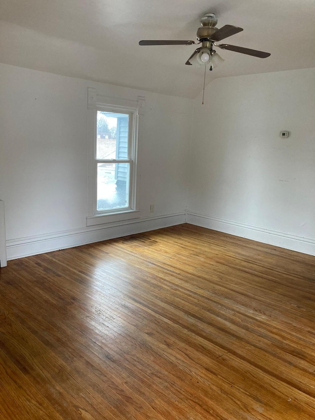 unfurnished room featuring ceiling fan, baseboards, vaulted ceiling, and wood finished floors