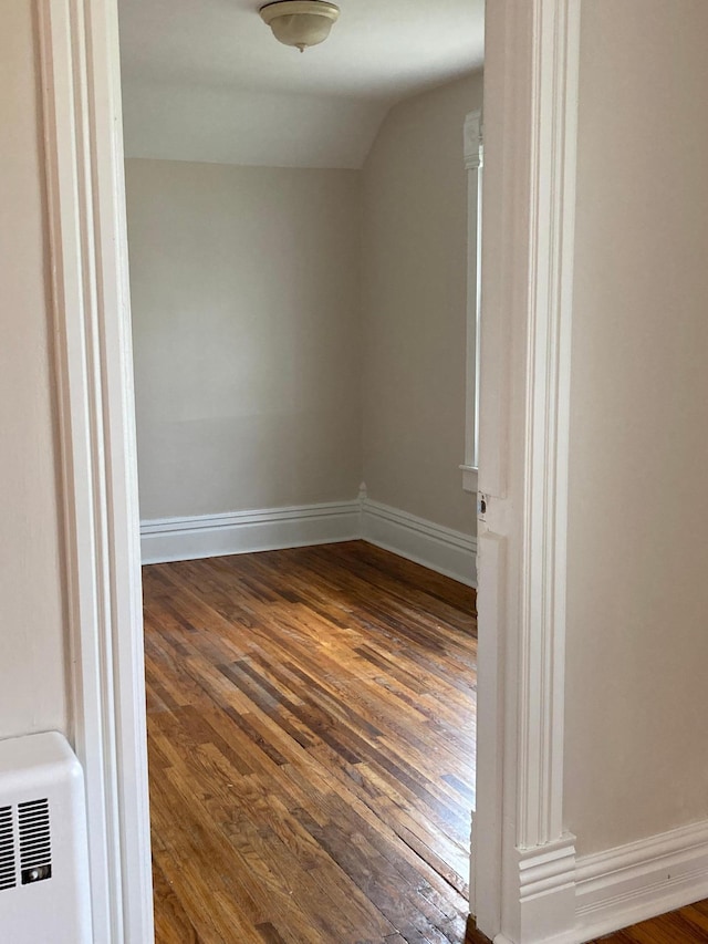 unfurnished room with lofted ceiling, baseboards, and dark wood-type flooring