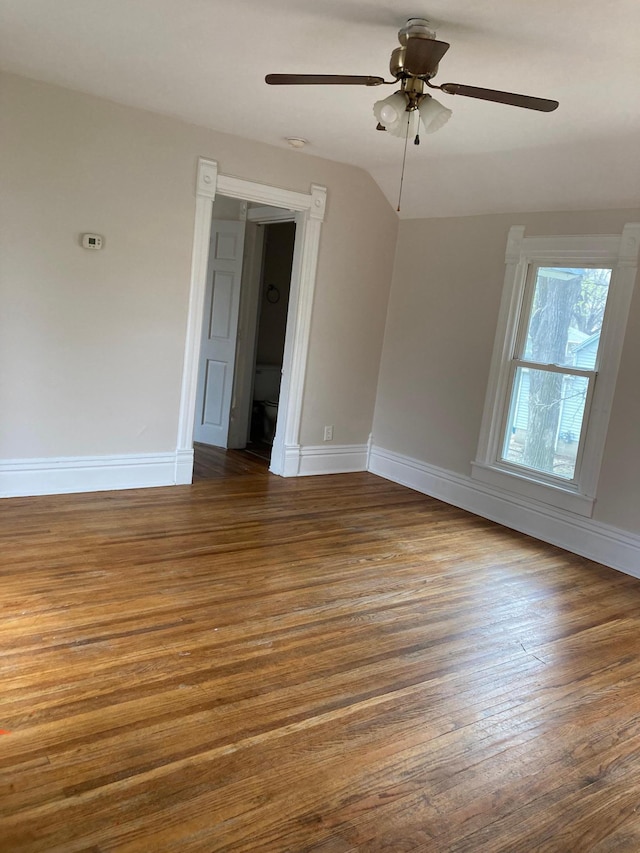 spare room with lofted ceiling, a ceiling fan, baseboards, and dark wood-type flooring