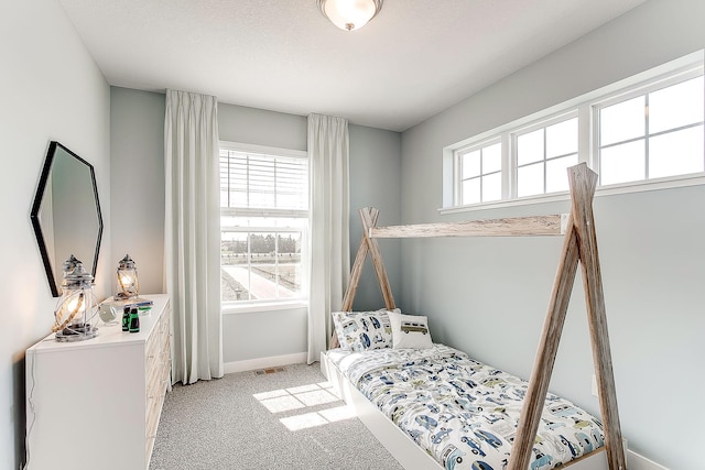 bedroom featuring light carpet, a textured ceiling, visible vents, and baseboards