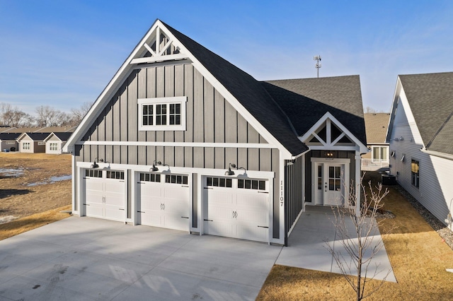 modern farmhouse style home featuring board and batten siding, roof with shingles, and a detached garage