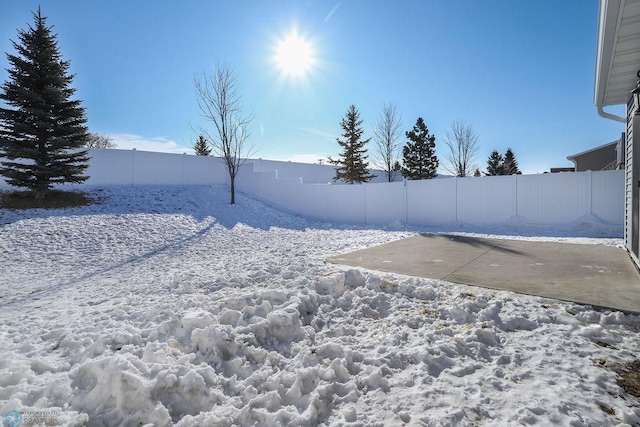 yard layered in snow with a patio area and fence