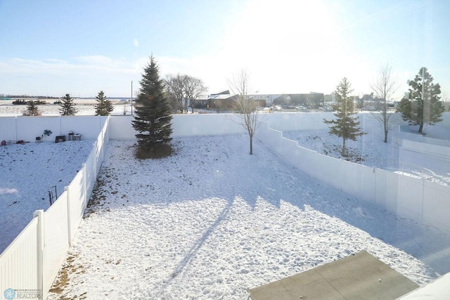 snowy yard with a fenced backyard