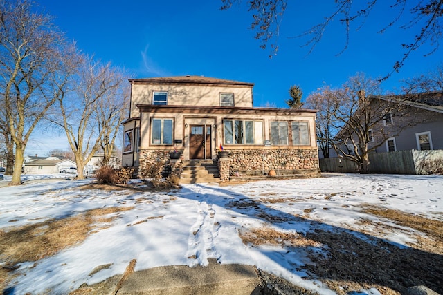 view of front of property with stone siding and fence