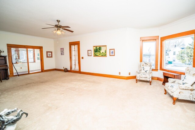 living area with crown molding, baseboards, a wealth of natural light, and carpet flooring