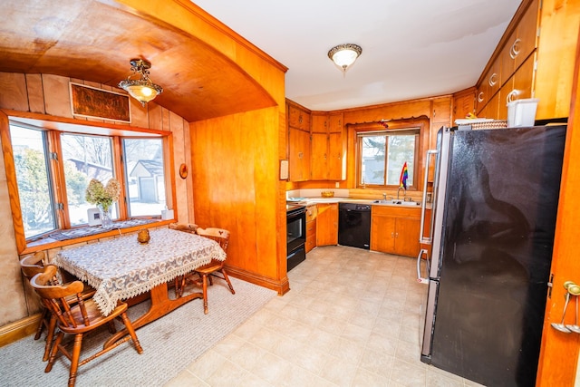 kitchen with lofted ceiling, light floors, light countertops, black appliances, and brown cabinetry