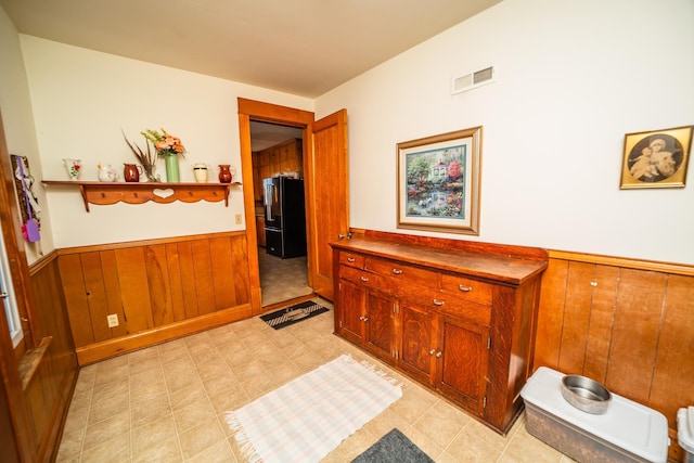 corridor featuring wooden walls, visible vents, and wainscoting