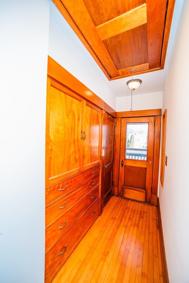 hall featuring wood ceiling, baseboards, and light wood finished floors