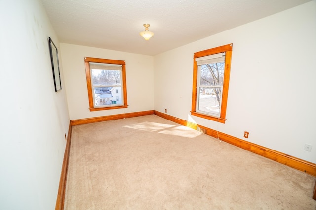 unfurnished room with baseboards, plenty of natural light, visible vents, and light colored carpet